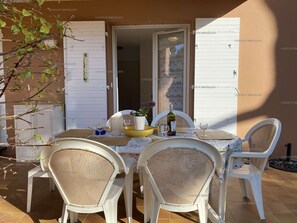 An outdoor dining area with a table set for four, surrounded by wicker chairs.