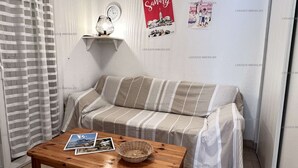 A cozy room with a striped sofa, a small table with a basket, and two posters on the wall.