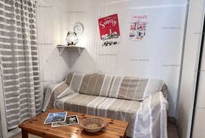 A cozy room with a striped sofa, a small table with a basket, and two posters on the wall.