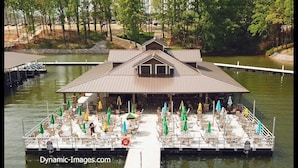 Een boot afgemeerd met terras en parasols, omgeven door bomen en water.