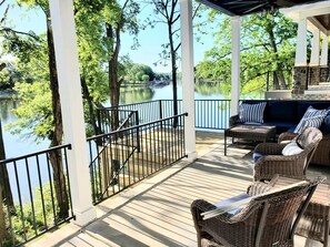 Eine überdachte Terrasse im Freien mit Korbmöbeln und Seeblick.