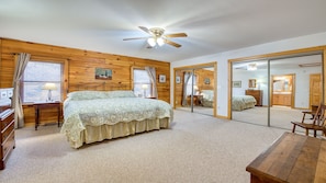 A bedroom with a bed, a dresser, a mirror, and a ceiling fan.