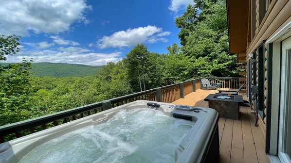 A hot tub on a wooden deck with a view of a forested mountain range. - Beautiful mountain view! SAUNA, HOT TUB, Pool Table, and Fast WIFI! Pet friendly (Waynesville)