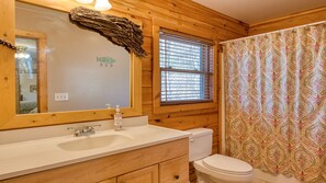 A bathroom with wooden walls, a white sink, a toilet, and a shower curtain with a paisley pattern. - Beautiful mountain view! SAUNA, HOT TUB, Pool Table, and Fast WIFI! Pet friendly (Waynesville)