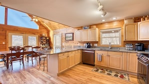 Una cocina estilo cabaña de madera con comedor, armarios de madera, horno empotrado y una estación para café.