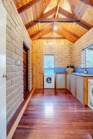 Une cuisine de taille réduite avec des poutres en bois, un mur en briques et un lave-linge.