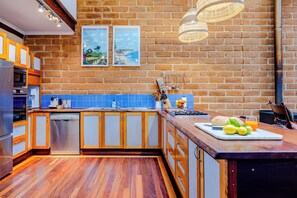Una cocina moderna con armarios de madera, salpicadero de azulejos azules y una lámpara colgante.