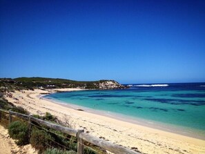 Une plage aux eaux turquoise et limpides, un rivage sablonneux et une clôture en bois.