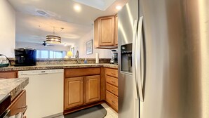 A modern kitchen with wooden cabinets, a stainless steel refrigerator, a built-in dishwasher, and a coffee maker.