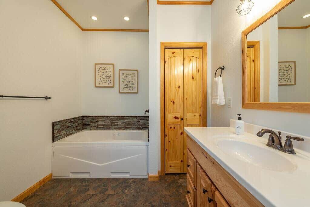 Un baño con bañera, lavabo, armarios de madera y una puerta.