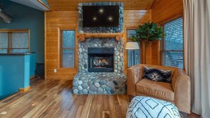 A cozy room with a stone fireplace, wooden ceiling, and a leather sofa.