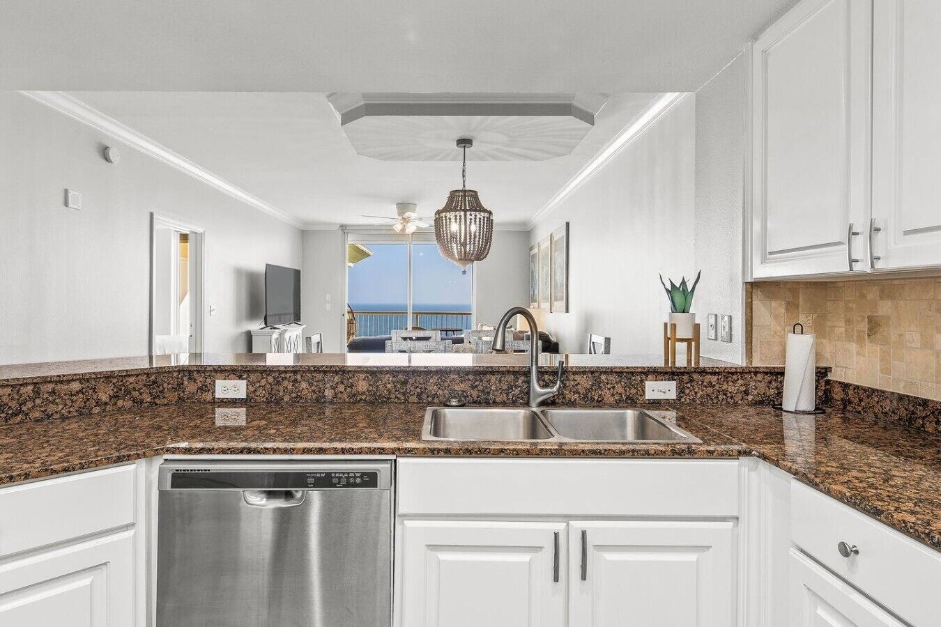 A modern kitchen with granite countertops, stainless steel appliances, and white cabinetry.