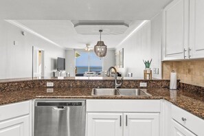 A modern kitchen with granite countertops, stainless steel appliances, and white cabinetry.