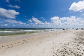 Una playa con huellas, olas y gente.
