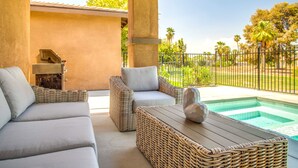 A covered outdoor seating area with wicker furniture, a pool, and a grill. - NEW! Glamorous Golf Getaway w/ Private Pool & Spa (Indio)