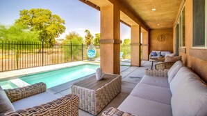 A covered outdoor area with a pool, wicker furniture, and a seating area with a view of the pool. - NEW! Glamorous Golf Getaway w/ Private Pool & Spa (Indio)