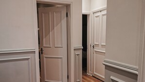 Ein Korridor mit Holzboden und weißen Türen mit dekorativen Verzierungen.