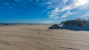 Une plage de sable avec des traces de pneus et un monticule de sable.