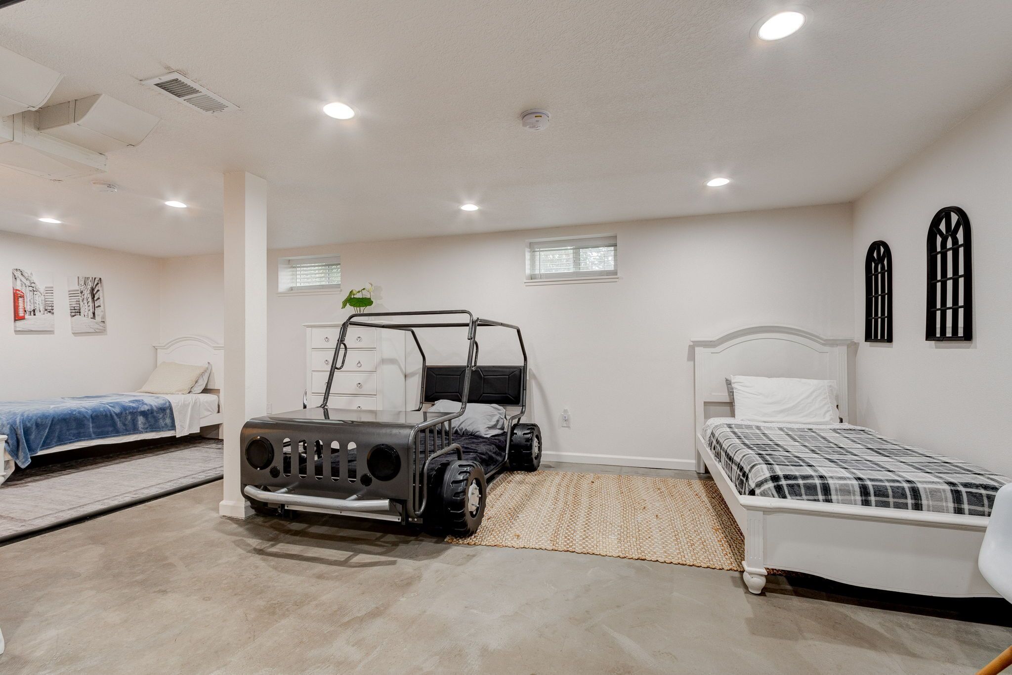 A bedroom with two beds, a large vehicle, and a small window.