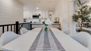 A modern kitchen with white cabinetry, stainless steel appliances, and a dining area with a white table and chairs.