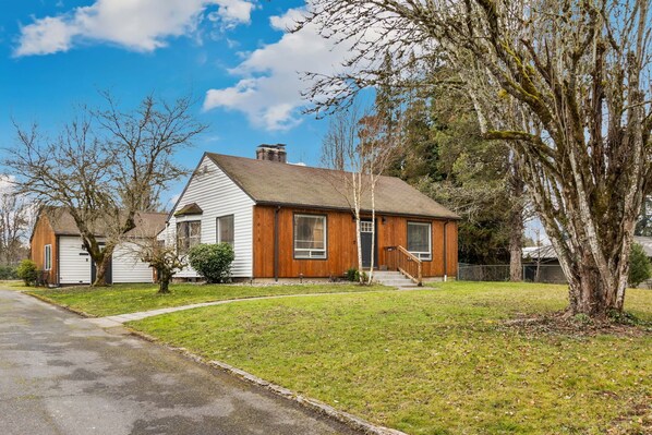 A single-story house with a front porch, a small front yard, and a driveway. - Updated home in Vancouver. King bed. (Vancouver)