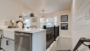 A modern kitchen with a central island, stainless steel appliances, pendant lighting, and decorative wall art.