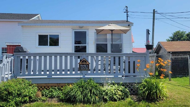 A house with a porch, a sign indicating it's a cottage rental, and a telephone number. - Beach vibes (Pointe-du-Chêne)