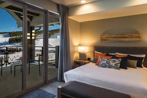 Relax in this serene hotel room with a large bed, nightstand, and sliding glass door offering a view of the snowy landscape.