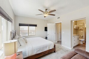 Relax in a spacious bedroom with a large bed, ceiling fan, and comfortable seating area.