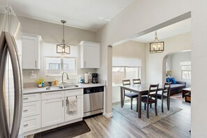 Enjoy meals in the kitchen with stainless steel appliances and a central island, adjacent to a dining area with a wooden table and outdoor views.