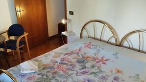 Ein Schlafzimmer mit Bett, Sessel, Schreibtisch und Kleiderschrank.