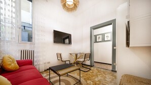 Ein modernes Wohnzimmer mit einem roten Sofa, einem kleinen Tisch und einem an der Wand befestigten Fernseher.