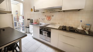 Eine Küche mit weißen Schränken, einem Edelstahlbackofen, einer Spüle und einem Fenster.