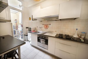 A kitchen with white cabinets, a stainless steel oven, a sink, and a window.