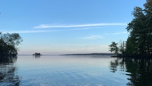 Un lago tranquilo con un kayak en primer plano y una isla a lo lejos.