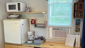 Cocina compacta con refrigerador, microondas, cafetera y ventana con persianas.