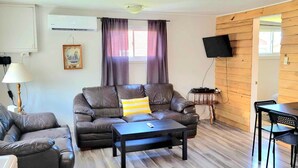 A living room with a sofa, a coffee table, and a dining area with a table and chairs. - Home by the beach (Pointe-du-Chene)