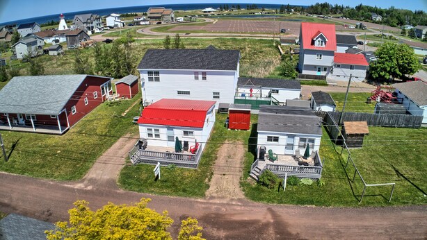 A residential area with houses, a dock, and a lighthouse in the background. - Home by the beach (Pointe-du-Chene)