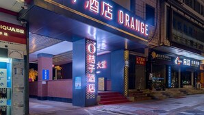 A hotel entrance with a prominent neon sign, a staircase leading to the entrance, and a visible side entrance.