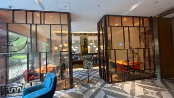 A modern interior with a blue armchair, geometric patterned floor, and traditional decor elements.