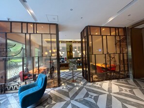 Um interior moderno com uma poltrona azul, piso com padrão geométrico e elementos de decoração tradicional.