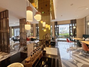 Um hall de hotel moderno com área de bar, disposição de assentos e janelas amplas com vista.