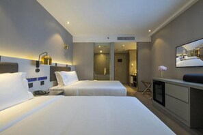 A hotel room with two beds, a desk, a mirror, and a shower area. - Orange Hotel Donghui Citymall Zengcheng Guangzhou (Guangzhou)