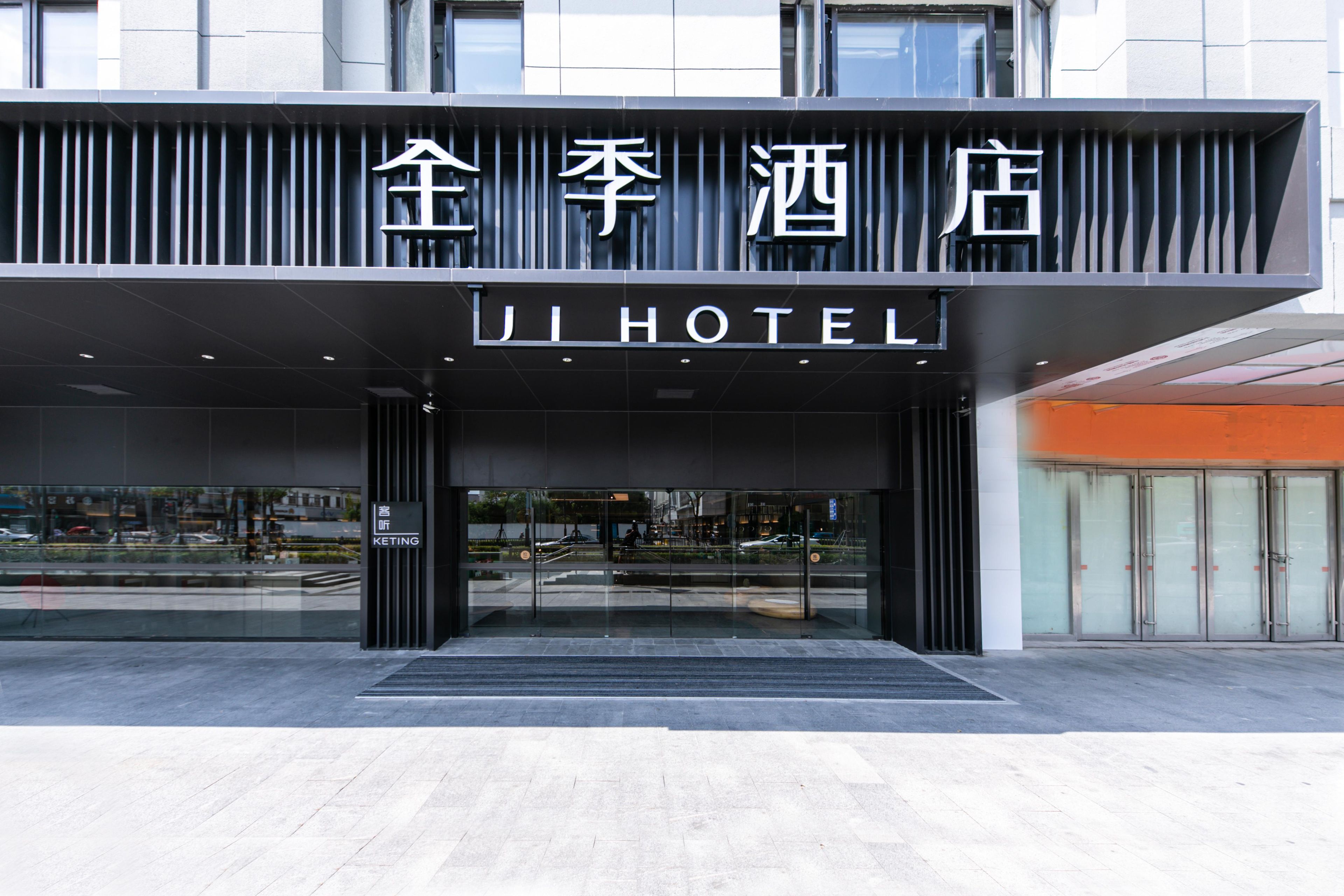 A hotel entrance with a modern facade, large glass doors, and a sign indicating the hotel name.