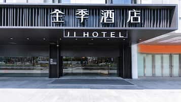 A hotel entrance with a modern facade, large glass doors, and a sign indicating the hotel name.