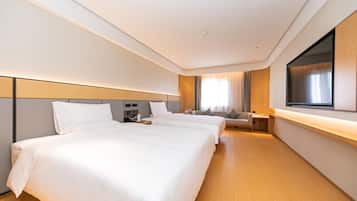 A hotel room with two beds, a TV, a desk, and a chair.