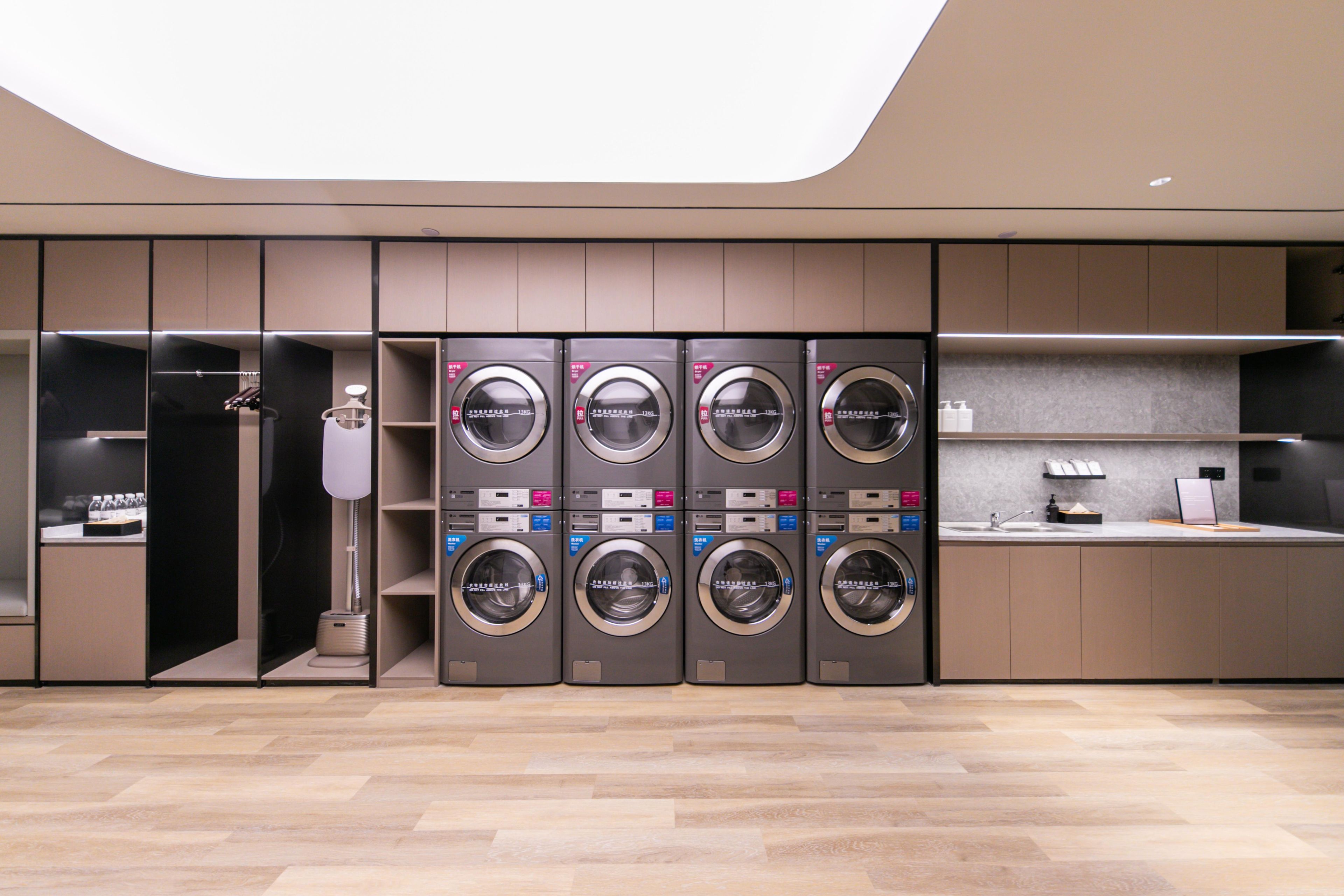 A modern laundry facility with multiple washing machines, a drying machine, and a sink area.