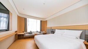 A modern hotel room with a large bed, a seating area with a table, and a window with curtains. - Ji Hotel Guanqian Street Chayuanchang Metrostation (Suzhou)