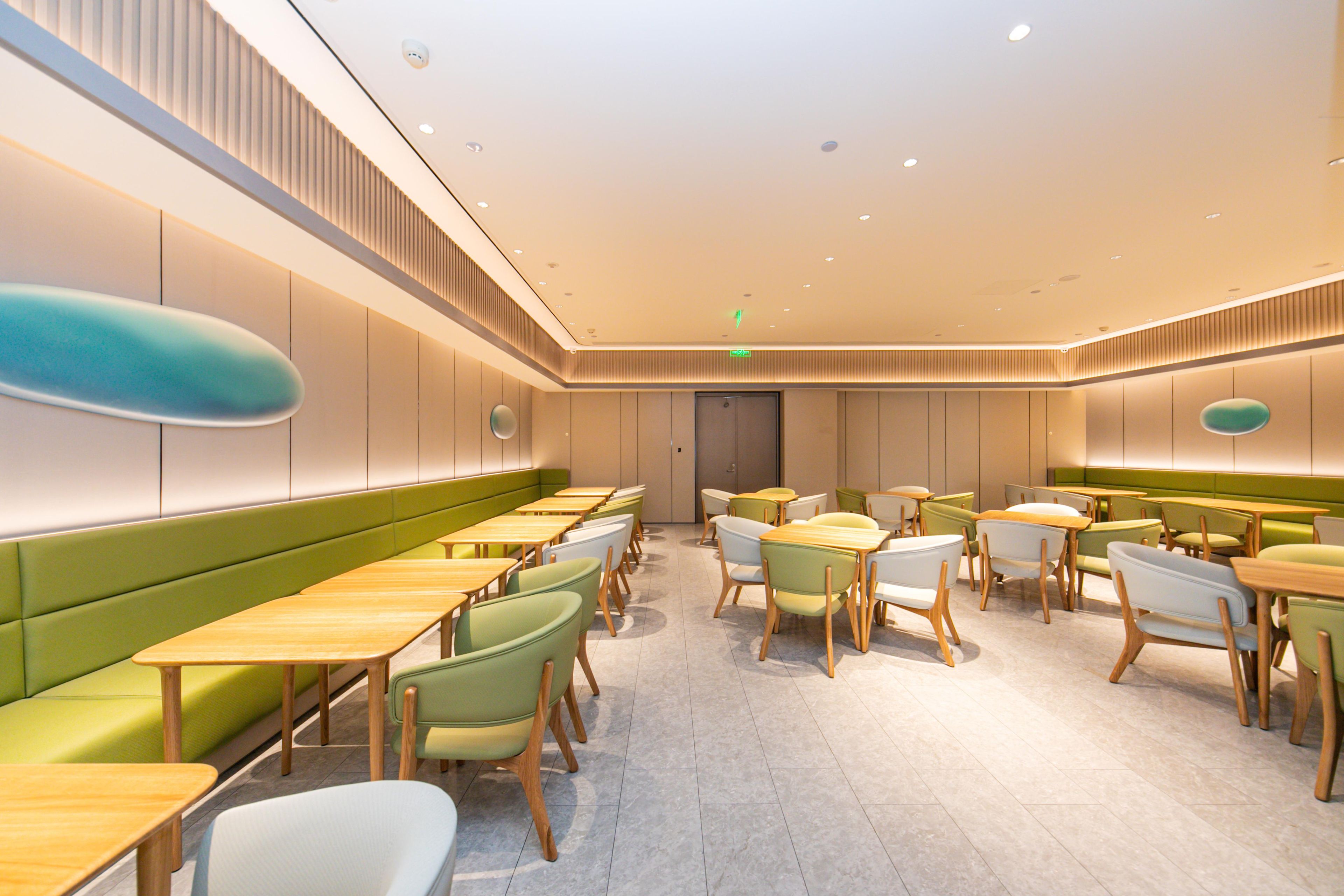 Un espace de restauration moderne, doté de banquettes et de tables, d’un éclairage encastré et d’une palette de couleurs neutres.
