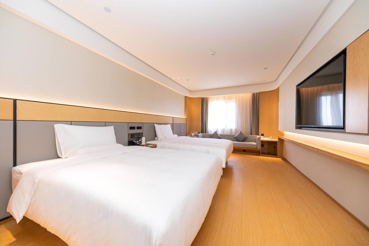 Quarto de hotel com duas camas, televisão, escrivaninha e uma cadeira.
